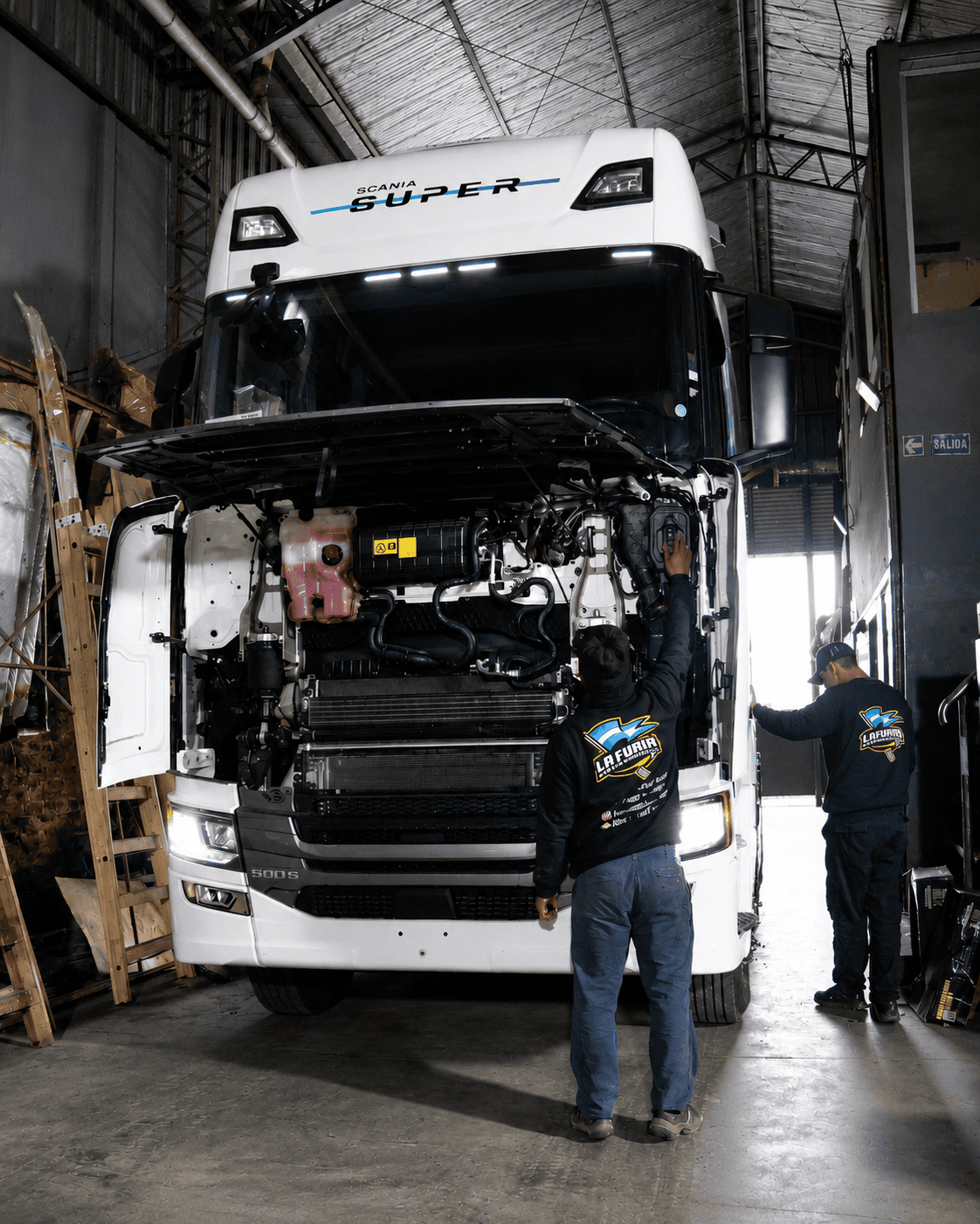 Técnicos trabajando en la parte frontal de un camión Scania